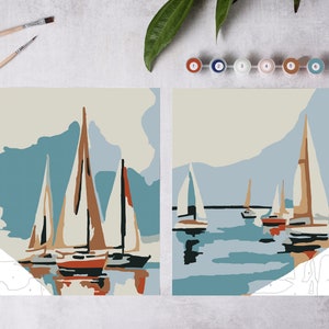 May include: Two paint by numbers canvases depicting a seascape with sailboats. The canvases are on a white surface with paint pots and brushes.