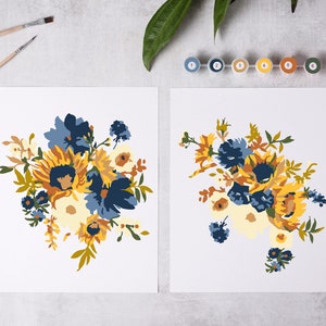 Könnte beinhalten: Zwei Malen-nach-Zahlen-Leinwände mit Blumenarrangements mit Sonnenblumen, blauen und weißen Blumen und grünen Blättern. Die Leinwände befinden sich auf einer weißen Oberfläche mit Farbtöpfen und Pinseln.
