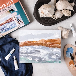 May include: A seascape painting kit with a canvas, paint tubes, and painting knives. The kit includes a seashell and a wooden palette.