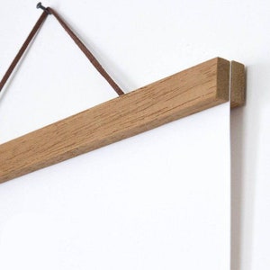 Pu&ograve; includere: Un portaposter in legno con un cordino in pelle marrone e un chiodo per appenderlo. Il portaposter &egrave; realizzato in legno naturale e ha un design semplice.