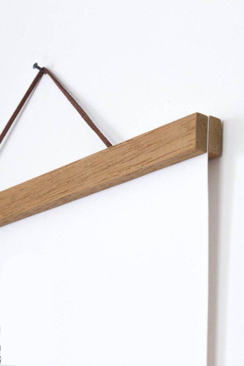 Pu&ograve; includere: Un portaposter in legno con un cordino in pelle marrone e un chiodo per appenderlo. Il portaposter &egrave; realizzato in legno naturale e ha un design semplice.