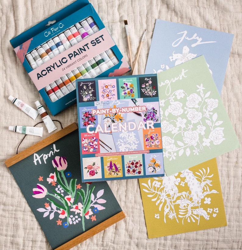 May include: An assortment of art supplies, including a paint-by-number calendar, acrylic paint set, and individual paint tubes. The calendar features floral designs, and the paint set includes 24 vibrant colors. The word "April" is visible on a framed artwork.