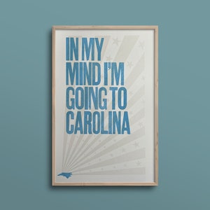 Pu&ograve; includere: Una stampa incorniciata con sfondo bianco e testo blu che recita "In my mind I'm going to Carolina". La stampa presenta una silhouette blu dello stato della Carolina del Nord e un motivo a stella bianca.