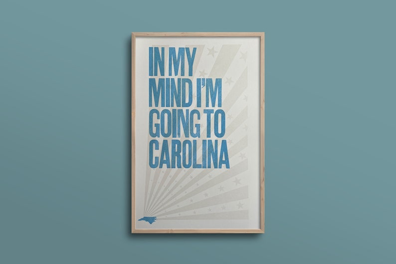 Pu&ograve; includere: Una stampa incorniciata con sfondo bianco e testo blu che recita "In my mind I'm going to Carolina". La stampa presenta una silhouette blu dello stato della Carolina del Nord e un motivo a stella bianca.