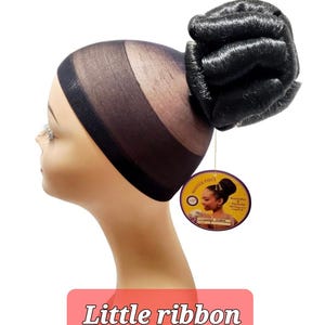 May include: A black hair bun with a net base, attached to a mannequin head. The bun is made of synthetic hair and is labeled "Little ribbon (color # 1)". A round tag is attached to the bun.
