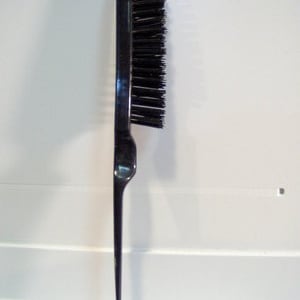 May include: A black plastic hair brush with a long, thin handle. The bristles are black and the handle is smooth.