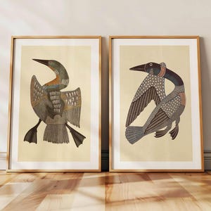 May include: Two framed art prints featuring stylized illustrations of birds. The birds have detailed feather patterns in shades of brown, gray, and black, set against a cream-colored background. The frames are a natural wood color, adding a warm touch to the artwork.