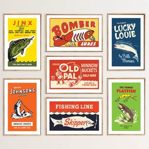 May include: A collection of framed vintage fishing-themed prints. Each print features bold colors and retro graphics, including illustrations of fish, lures, and text such as "Jinx", "Bomber Lures", and "Lucky Louie".