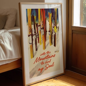 May include: Framed vintage-style poster featuring a colorful illustration of skis against a mountain backdrop. The poster has the text "into the Mountains to find my Soul" in red script. The poster is leaning against a wall next to a bed.