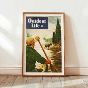 Op de afbeelding: Een vintage poster voor het tijdschrift Outdoor Life met een man die in een kano een rivier afvaart in een bosrijke omgeving. Een eland is zichtbaar op de achtergrond.