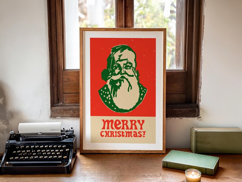 Op de afbeelding: Een ingelijste poster met een rode achtergrond waarop een cartoonillustratie van de kerstman met een groene hoed en baard te zien is. De tekst "merry christmas!" is in groen en wit onder de illustratie gedrukt.