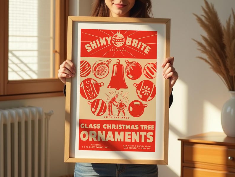 Op de afbeelding: Een vintage poster die reclame maakt voor Shiny Brite glazen kerstboomversieringen. De poster heeft een rood en wit kleurenschema met een cirkel van ornamenten en een bel in het midden. De tekst luidt "Shiny Brite Registered, American Made, Glass Christmas Tree Ornaments, Factories: E.W. Glass Works, Inc., Main Office & Display Rooms: Max Schardt & Son, Inc."