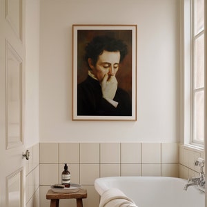 Op de afbeelding: Een ingelijst portret van een man in een donker pak met een witte handschoen die zijn mond bedekt. Het portret hangt aan een witte muur in een badkamer met een wit bad en witte tegels.