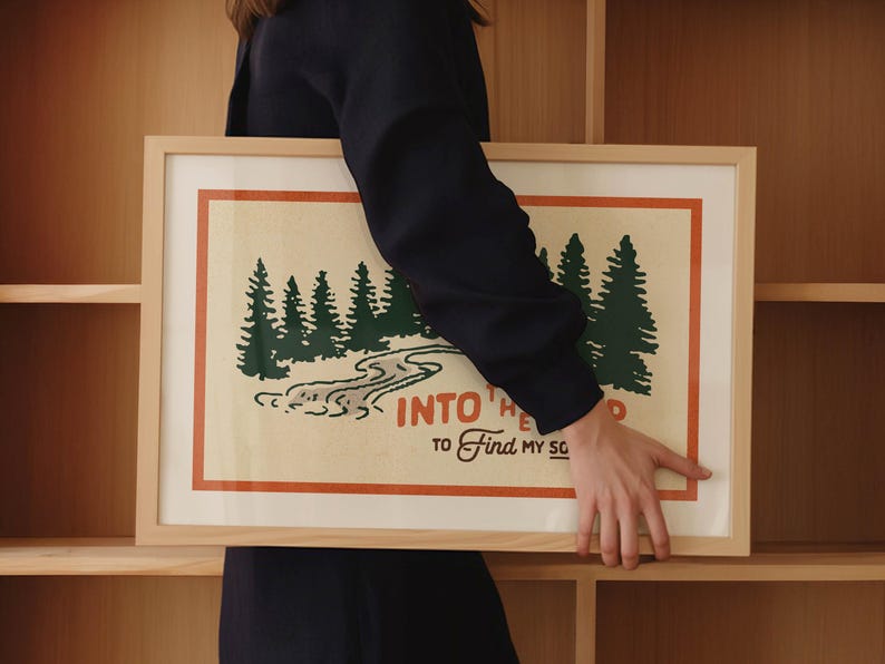 Puede incluir: Una impresi&oacute;n enmarcada con una est&eacute;tica vintage que presenta una escena de bosque verde con un r&iacute;o sinuoso y el texto "Into the Wild to Find My Soul".
