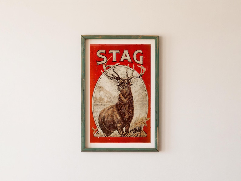 May include: A vintage framed poster with a red background and the word "STAG" in large, black letters. A detailed illustration of a stag with large antlers is featured in the center of the poster.