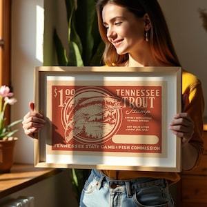 May include: Framed vintage Tennessee Trout Stamp art print. The print features a red and beige design with a trout illustration and text. The frame is a light wood colour.