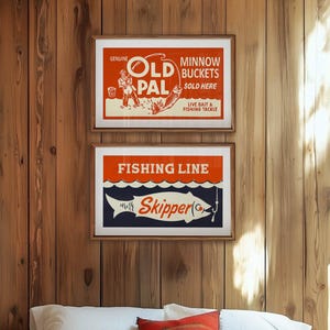 May include: Two framed vintage fishing-themed posters. The top poster reads "Old Pal Minnow Buckets Sold Here." The bottom poster says "Fishing Line Skipper." Both posters have a retro design with red, white, and blue colors.