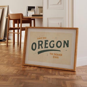 May include: A framed print with a beige background and a green and orange graphic that says "Oregon, The Beaver State, Since 1859".