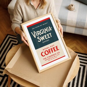 May include: A framed vintage advertisement for Virginia Sweet Brand Steel Cut Coffee. The design features a red and blue color scheme with the text "Virginia Sweet Brand" prominently displayed. The frame is light-colored wood.
