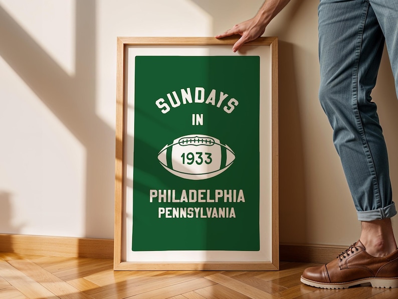 K&ouml;nnte beinhalten: Ein gerahmter Druck mit gr&uuml;nem Hintergrund und wei&szlig;em Text, der "Sundays in 1933 Philadelphia Pennsylvania" lautet. Eine wei&szlig;e Fu&szlig;ballgrafik ist mittig auf dem Druck platziert.