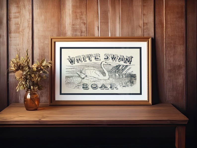 May include: A white ceramic mug with a black handle and the text "But First, Coffee" in a bold, black font. The mug is set against a blurred background, suggesting a cosy setting.