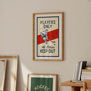 Pu&ograve; includere: Stampa incorniciata a tema hockey con un design vintage. L'opera presenta un'illustrazione di un giocatore di hockey, una striscia rossa e il testo "Players Only, All Others Keep Out". La stampa &egrave; in una cornice di legno.