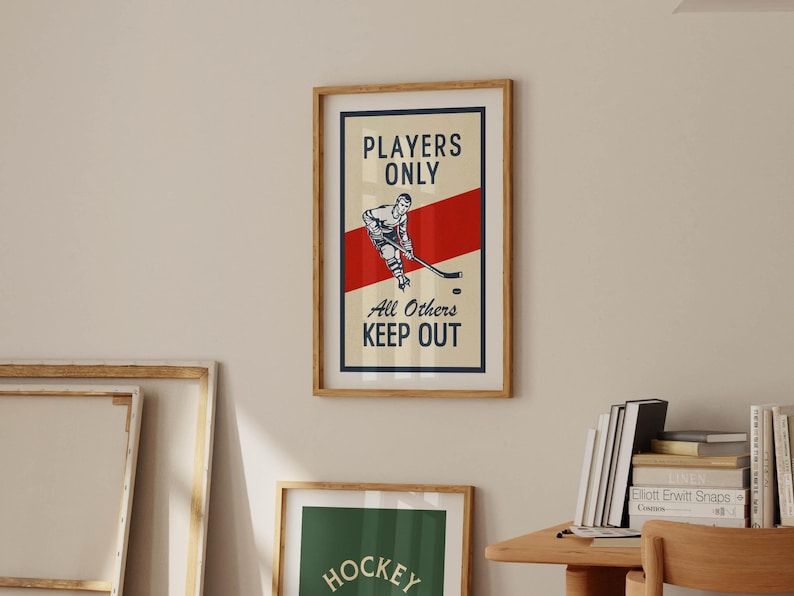 Pu&ograve; includere: Stampa incorniciata a tema hockey con un design vintage. L'opera presenta un'illustrazione di un giocatore di hockey, una striscia rossa e il testo "Players Only, All Others Keep Out". La stampa &egrave; in una cornice di legno.