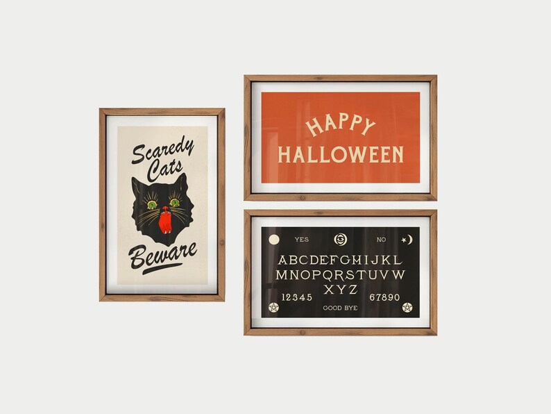 May include: Three framed Halloween-themed prints. One features a black cat with the text "Scaredy Cats Beware." Another has "Happy Halloween" on an orange background. The third is a Ouija board.