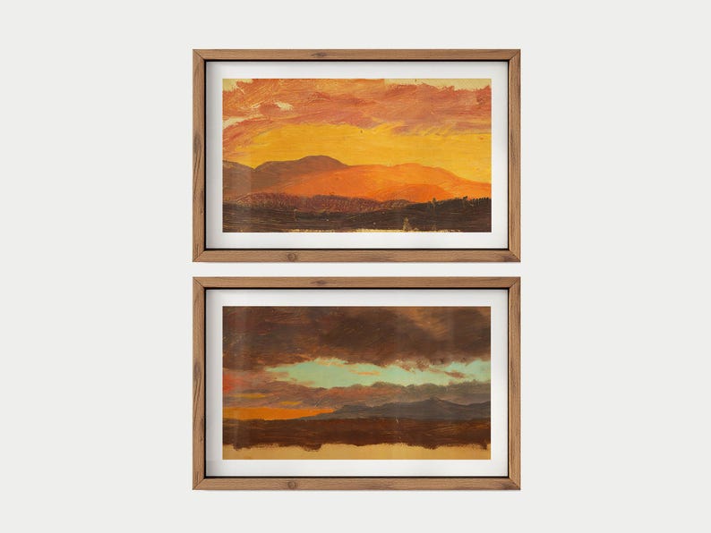 May include: Two framed landscape paintings. The top painting depicts a sunset with orange and yellow hues over mountains. The bottom painting shows a similar landscape with darker colors and a hint of blue sky. Both are in wooden frames.