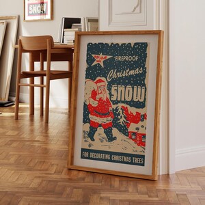 Op de afbeelding: Vintage kerstversiering poster met sneeuw, met een cartoon kerstman die een zak met cadeaus draagt. De poster heeft een blauwe achtergrond met witte sneeuwvlokken en de tekst "Fireproof Christmas Snow" in rood en wit. De poster bevat ook de tekst "Voor het versieren van kerstboom".