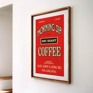 May include: A framed vintage coffee advertisement with a red background. The text reads "MORNING SIP DRY ROAST COFFEE" in a decorative font. The frame is a warm brown colour. The text includes "ALEX. SHEPP & SONS, INC. PHILADELPHIA".