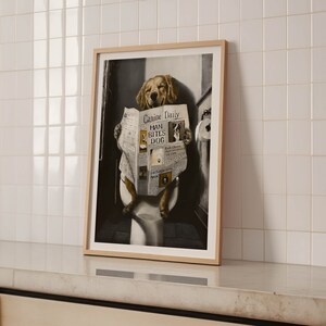 May include: A framed print of a golden retriever dog sitting on a toilet and reading a newspaper with the headline "Canine Daily: Man Bites Dog".