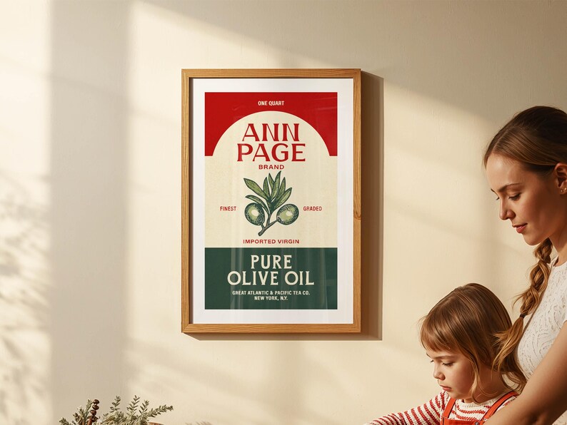 May include: A framed vintage-style print featuring "ANN PAGE BRAND" olive oil. The design includes a red and cream color scheme with the text "PURE OLIVE OIL" and an illustration of olive branches. The print is in a wooden frame.