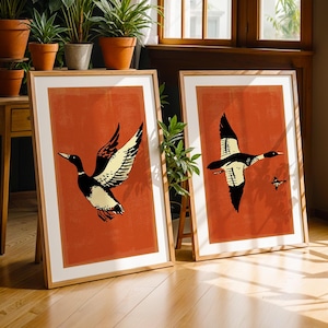 May include: Two framed prints with a red background and black and white illustrations of ducks in flight. The prints are in wooden frames.