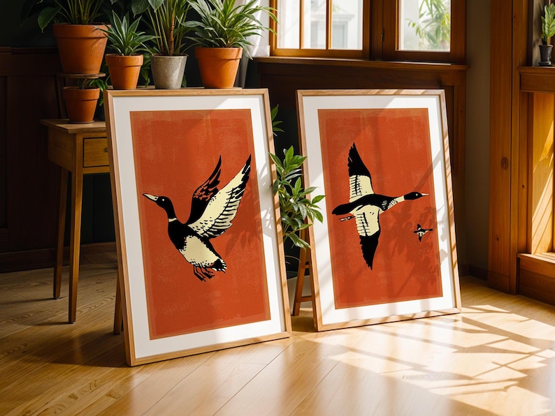 May include: Two framed prints with a red background and black and white illustrations of ducks in flight. The prints are in wooden frames.