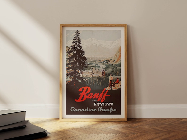May include: Vintage travel poster advertising Banff in the Canadian Rockies. The poster features a scenic view of the mountains and a large pine tree in the foreground. The text "Banff in the Canadian Rockies" and "Canadian Pacific" are printed in red and black.