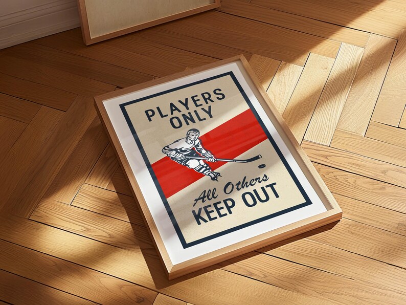 Pu&ograve; includere: Stampa artistica incorniciata a tema hockey. L'opera presenta un'illustrazione di un giocatore di hockey con una striscia diagonale rossa e il testo "Players Only, All Others Keep Out". La stampa &egrave; in una cornice di legno chiaro.