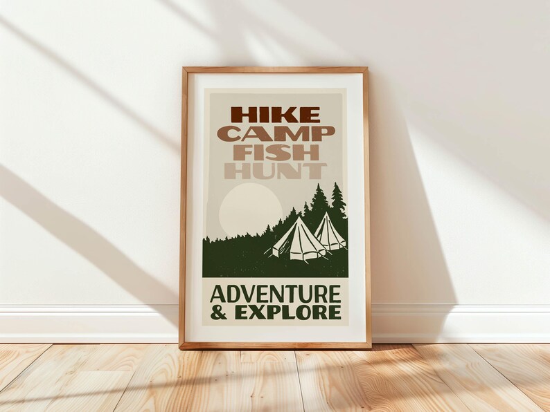 May include: A framed print with a vintage aesthetic featuring the text "HIKE CAMP FISH HUNT ADVENTURE & EXPLORE" in brown and white lettering. The print depicts a forest scene with two tents and a sun in the background.