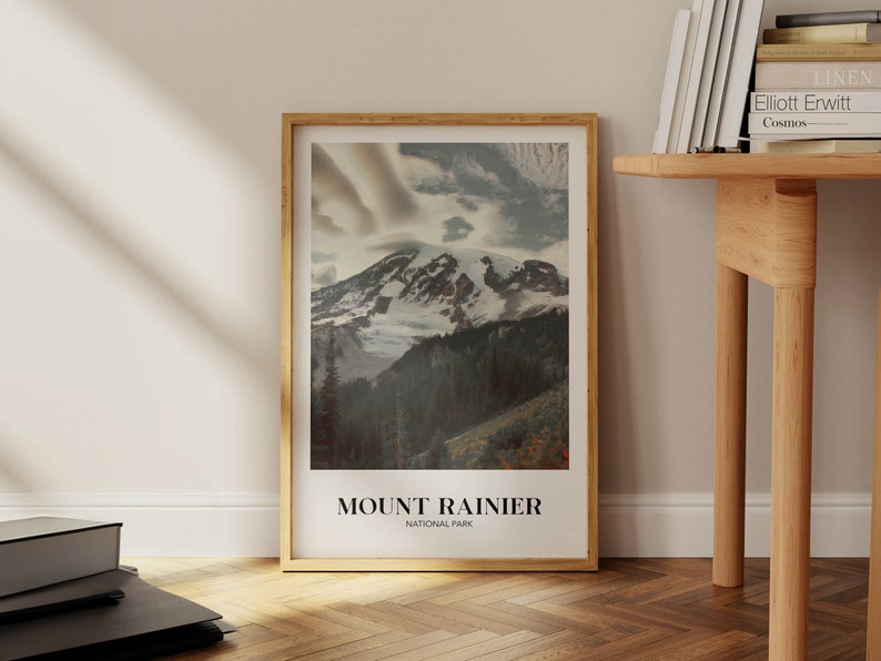 K&ouml;nnte beinhalten: Ein gerahmtes Poster mit einem Foto vom Mount Rainier National Park. Das Bild zeigt einen schneebedeckten Berggipfel mit Wolken am Himmel. Der Text "MOUNT RAINIER NATIONAL PARK" ist unter dem Bild gedruckt.