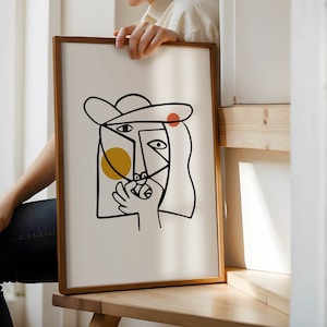 May include: A framed abstract line drawing of a person's face with a hat, yellow and red circles, and a white background.