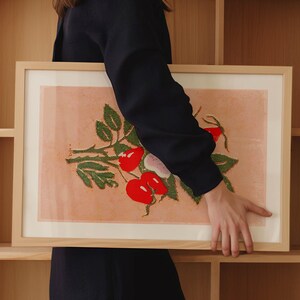May include: A framed print of a botanical illustration featuring a green plant with red berries on a peach background.