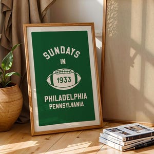K&ouml;nnte beinhalten: Ein gerahmtes gr&uuml;nes Poster mit wei&szlig;em Text, der "Sundays in 1933 Philadelphia Pennsylvania" lautet, und einer wei&szlig;en Fu&szlig;ballgrafik.