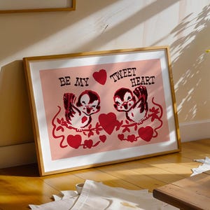 May include: A framed print with a pink background featuring two cartoon birds with red hearts and the text "Be My Tweet Heart".