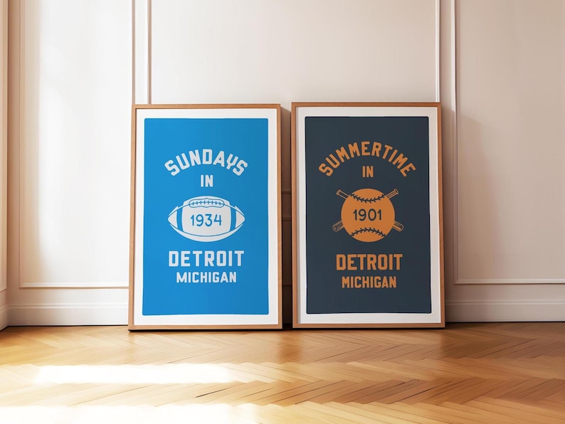 Peut inclure: Deux impressions encadr&eacute;es sur le th&egrave;me du sport vintage. L'impression de gauche est bleue avec un ballon de football blanc et le texte "Sundays in 1934 Detroit Michigan". L'impression de droite est bleu fonc&eacute; avec un ballon de baseball blanc et le texte "Summertime in 1901 Detroit Michigan".