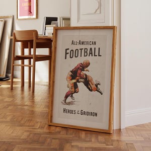 May include: A vintage poster with a brown wooden frame. The poster features a black and white illustration of two football players in action. The text on the poster reads "All-American FOOTBALL Heroes of the GRIDIRON".