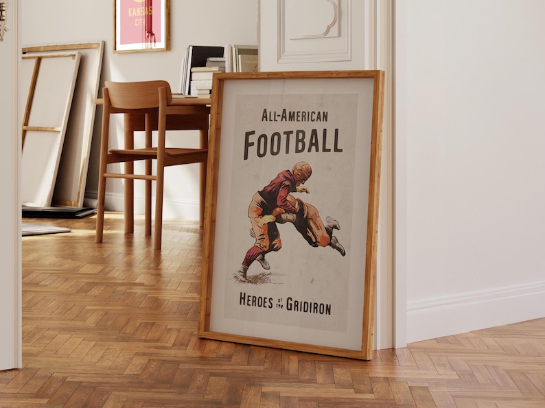 May include: A vintage poster with a brown wooden frame. The poster features a black and white illustration of two football players in action. The text on the poster reads "All-American FOOTBALL Heroes of the GRIDIRON".