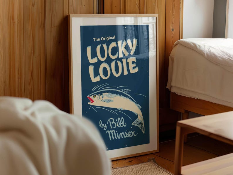 May include: Framed art print featuring a vintage-style illustration of a fish with the text "LUCKY LOUIE" in large, white, bold letters. The artwork is set against a dark blue background, with the artist's name at the bottom.