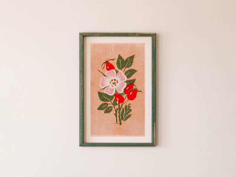 May include: A framed print of a pink and white flower with red berries on a light pink background. The frame is a light green color.