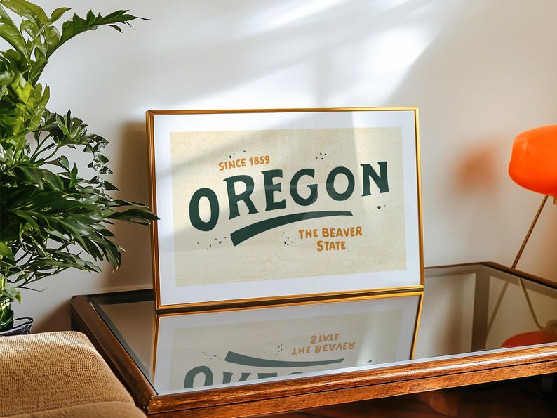 May include: A gold framed print with a vintage design featuring the text "Oregon, Since 1859, The Beaver State" in green and black lettering on a cream background.