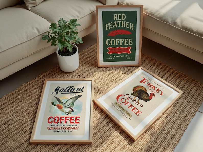 May include: Three framed vintage coffee advertisements. One features a mallard duck, another a turkey, and the third, a red feather. The frames are light wood, and the posters have a retro design with text and illustrations.